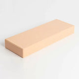 Beige rectangular sharpening stone for woodworking tools on a white background