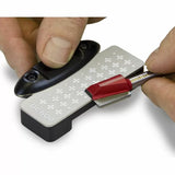 Sharpening a red router bit on a diamond bench stone with hands holding both tools