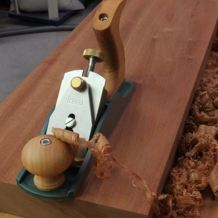 Hand plane smoothing wood surface with wood shavings, woodworking hand tool in use