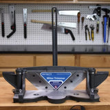 Miter trimmer tool on workbench in woodworking shop with hand tools on pegboard wall