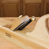 Wooden jointer hand plane with brass fittings on a woodworking bench