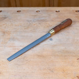 A half round rasp on a wooden work bench.