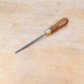 A round rasp sitting on a wooden bench.