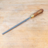 A round rasp sitting on a wooden bench.