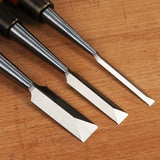 Set of three woodworking chisels with sharp beveled edges on a wooden surface