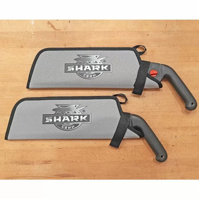 Two Japanese-style pull saws with black handles and gray protective sheaths on a wooden surface