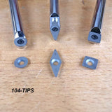 Three carbide insert cutter tips for woodworking displayed on a wooden surface