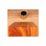 Wood finishing oil jar on workbench behind polished wooden block with visible grain.