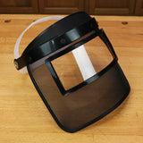 Clear face shield with mesh visor for woodworking safety on a wooden workbench