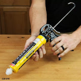 Person using a yellow caulking gun on a woodworking bench, applying adhesive sealant