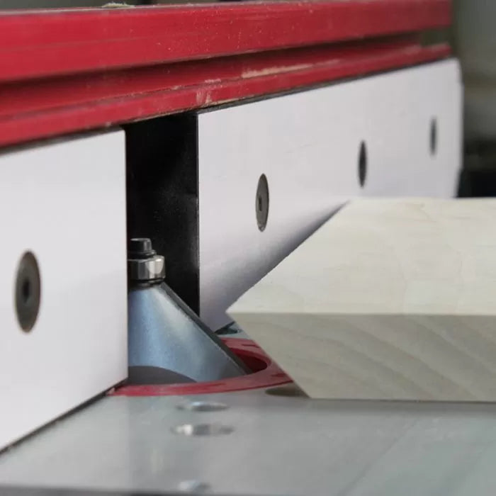 Router table with a chamfer router bit cutting the edge of a wood board