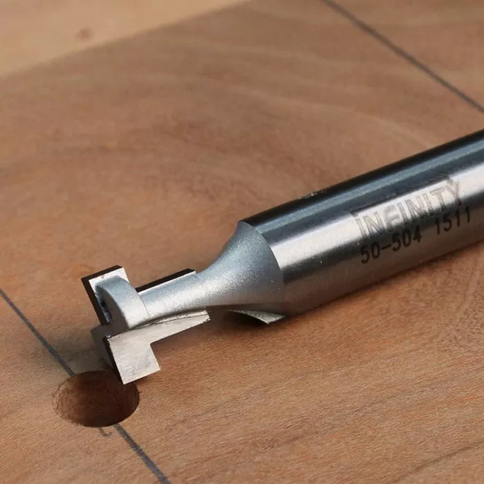 Dovetail router bit cutting clean groove in hardwood panel for woodworking joinery
