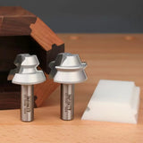 Two woodworking router bits with steel shanks and silver cutting edges on a wooden surface.