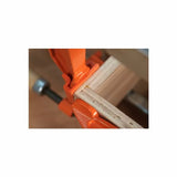 Wood glue-up with orange woodworking clamps securing a mitered joint on a workbench