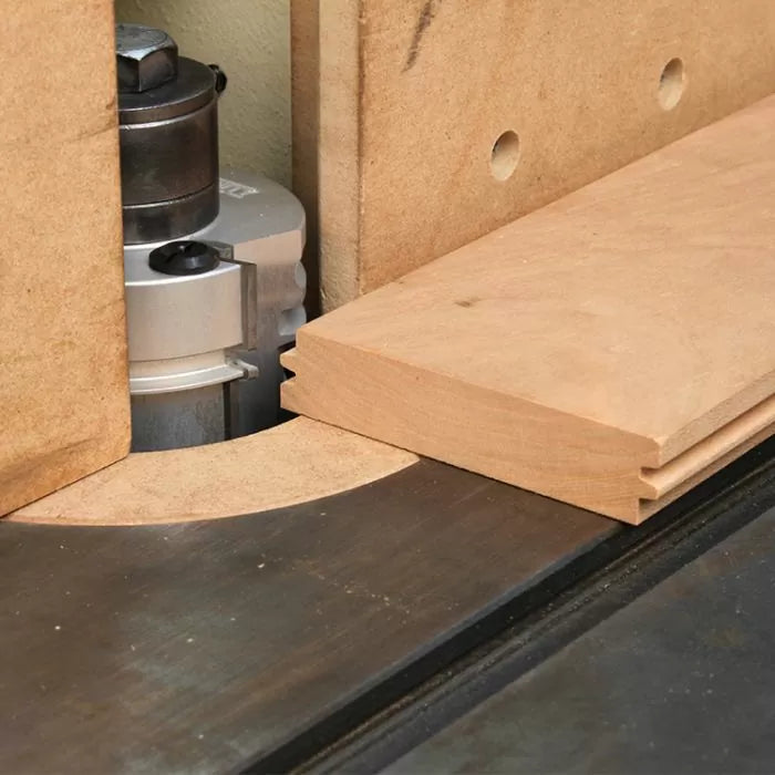 Router table with fence cutting groove in wooden board, woodworking tool close-up