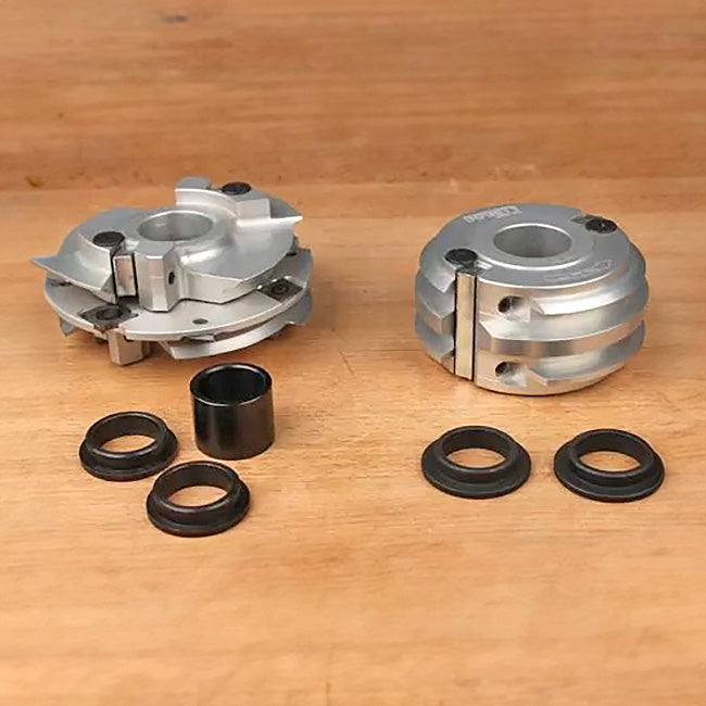 Woodworking cutter heads with bushings and spacers on a wooden surface