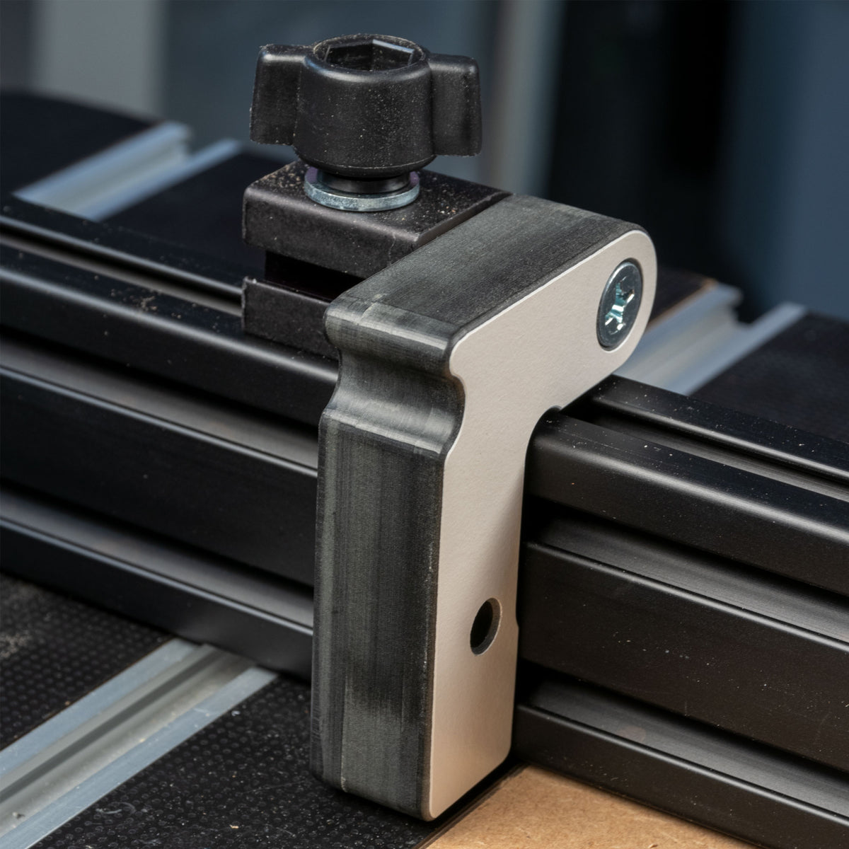 Aluminum router table fence stop block attached to a T-track woodworking fence