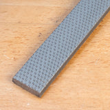 Flat chisel with textured steel blade on wooden surface, woodworking tool closeup