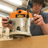Woodworker using a Triton router on a wooden board in a workshop