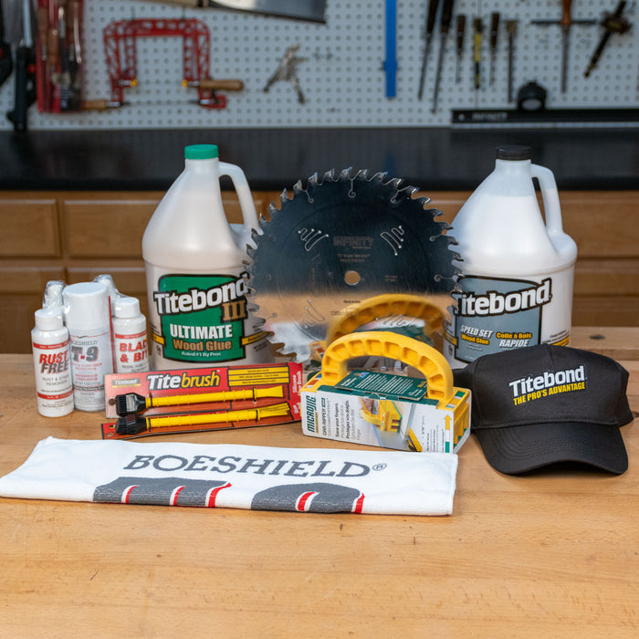 Woodworking prize pack with saw blade, wood glue, push block, cleaning supplies, and Titebond hat displayed on a workbench.