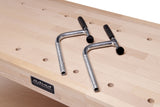 Two dog hole clamps laying on a wood Ramia workbench.