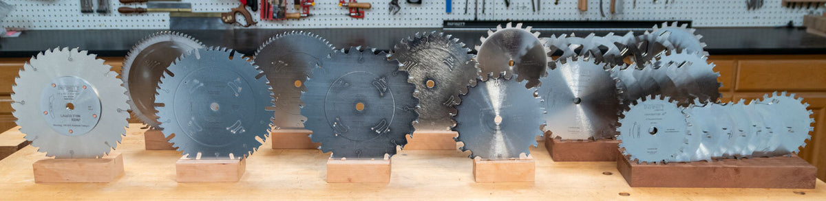 Collection of table saw blades on wood workbench.