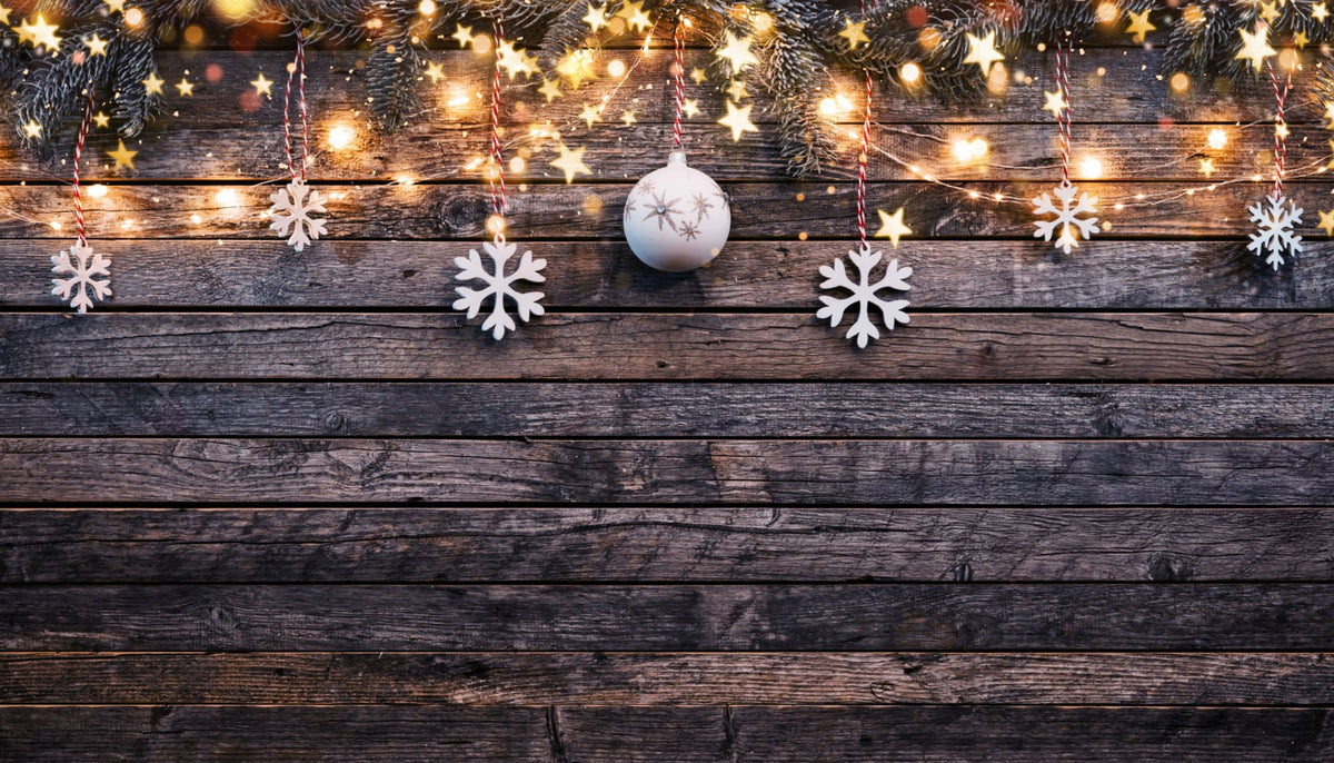Rustic wood background with Christmas lights, pine branches, snowflakes, and festive ornament