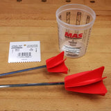 Woodworking epoxy mixing accessories with plastic cup, red paddles, and notched spreader on workbench.