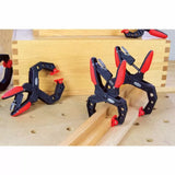 Corner clamps with red grips holding wooden boards for woodworking projects