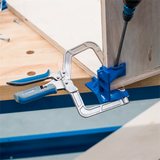 Pocket hole clamp securing plywood corner on workbench during woodworking assembly