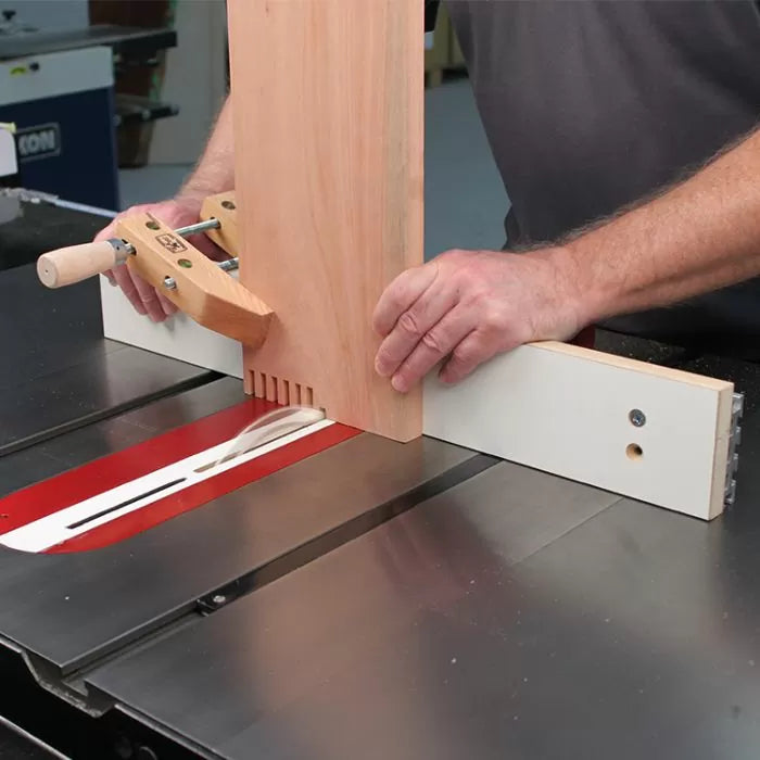 Woodworker using a table saw with a box joint jig to cut evenly spaced slots in a wooden board