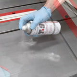 Hand spraying T-9 lubricant on a table saw for corrosion protection and tool maintenance