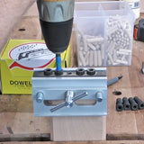 Woodworker using a dowel jig and drill on a wooden board with dowel pins nearby