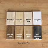 Pine wood samples showing finishes: bare, clear wax, neutral wax, liming wax, dark oak wax, medium oak wax, walnut wax, and black patinating wax, on a wooden surface.
