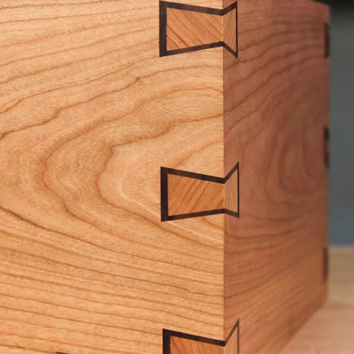 Close-up of a wooden box corner with precision inlaid dovetail joints for woodworking.
