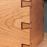 Close-up of a wooden box corner with precision inlaid dovetail joints for woodworking.