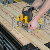 Woodworker using a router and jig system to cut precise grooves in a workbench top