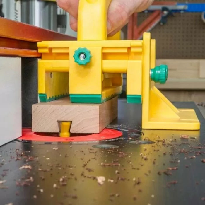 Push block guiding wood over router table with dovetail bit and safety features visible
