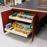 Woodworking table cabinet with open drawers holding router table accessories and woodworking tools.