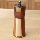 Handcrafted wooden pepper mill with striped wood pattern on workshop table
