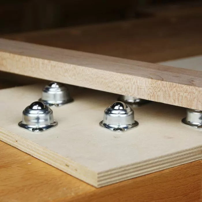 Wood panel resting on a board with steel ball bearing rollers for smooth woodworking support