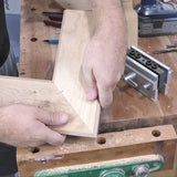 Woodworker holding mitered corners of wood pieces on workbench for precise joinery