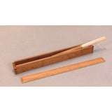 Wooden dovetail box with removable lid, holding thin wood strips on a light surface