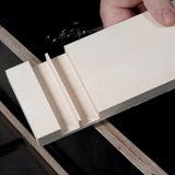 Hand holding a board with precise dado and groove cuts, woodworking joinery example