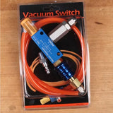 Vacuum switch kit with blue and silver components, orange tubing, and fittings on wood surface