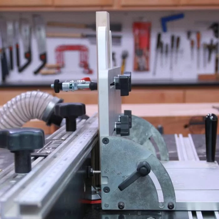 Router table fence with dust collection hose and adjustment knobs in woodworking shop